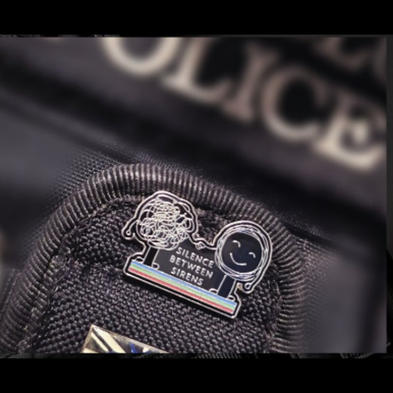 Silence Between Sirens enamel pin badge on a black police uniform